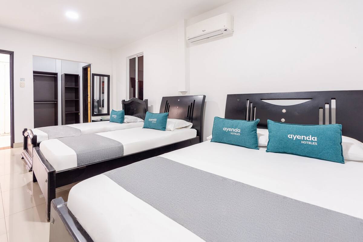 A hotel room with two beds, a wardrobe, and an air conditioning unit.