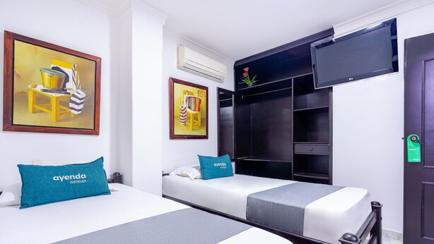 A hotel room with two beds, a flat-screen TV, a wardrobe, and artwork on the walls. - Hotel Union (Valledupar)