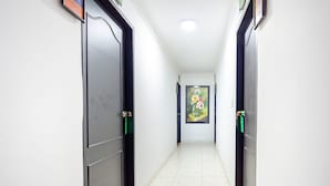 A hallway with doors on both sides, a tiled floor, and a painting on the wall. - Hotel Union (Valledupar)