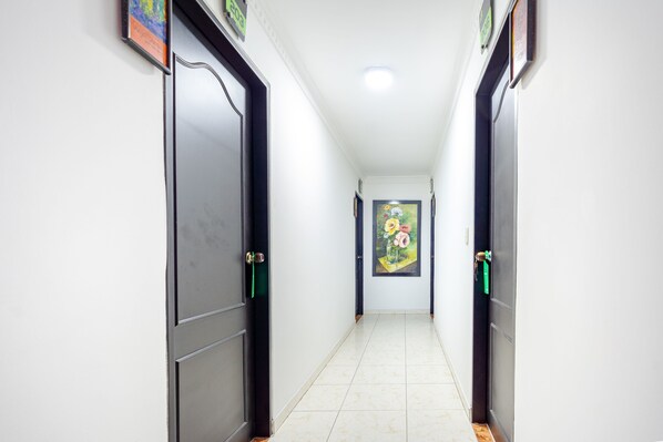 A hallway with doors on both sides, a tiled floor, and a painting on the wall. - Hotel Union (Valledupar)