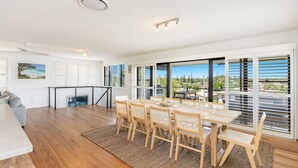A modern dining area with a large table, wicker chairs, and a view of the outdoors.
