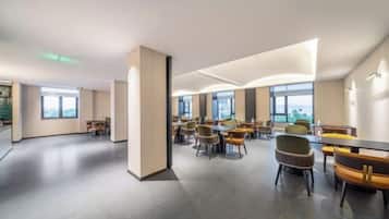 A spacious conference room with multiple tables and chairs, large windows, and a modern design.