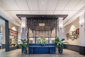 Un espace d’accueil avec un banc bleu, des plantes en pot et des tableaux encadrés accrochés aux murs.