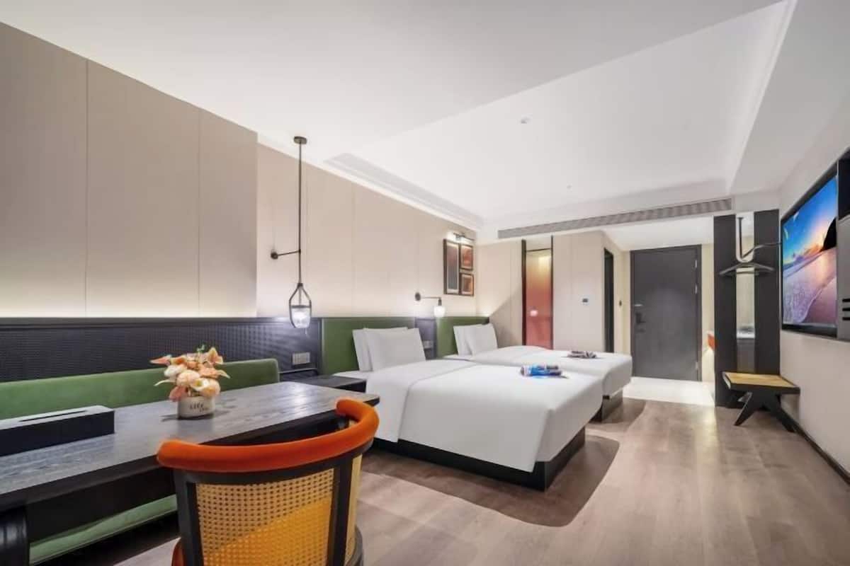 Une chambre d’hôtel avec un lit, un bureau, une chaise, une télévision et une porte.