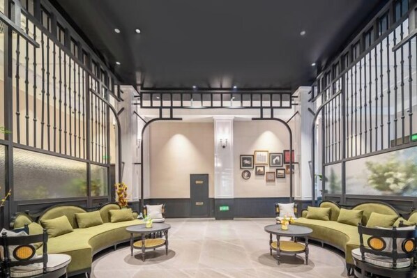 A modern interior with a curved sofa, round tables, and a large window. - Sijiqing Teng Hotel (Ningbo Jiangshan Wanda Plaza Branch) (Ningbo)
