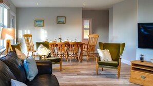 Ein modernes Wohnzimmer mit einer Ledersofa, einem Holzesstisch und Stühlen.