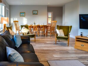 Uma sala de estar moderna com um sofá de couro, uma mesa de jantar de madeira e cadeiras.
