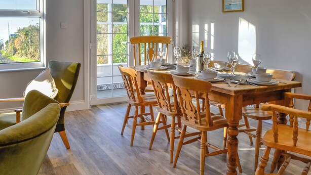 Ein Esszimmer mit einem Holztisch, gedeckt für sechs Personen, umgeben von sechs Holzstühlen.