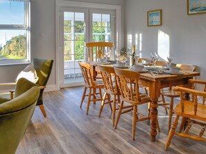 Een eetkamer met een houten tafel voor zes personen, omringd door zes houten stoelen.