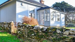 Ein Haus mit Steinmauer, Holztor und Glastür.