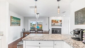 A modern kitchen with white cabinetry, a granite countertop, and a coffee machine. - Atlantic View Heated Pool/Spa/Firepit/Beach/Golf/Sleeps 12 (St. Augustine)