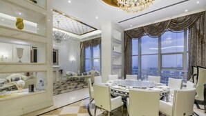 A spacious room with a round dining table, white chairs, a chandelier, and large windows with curtains. - Jiujiang Hotel (Qian'an)