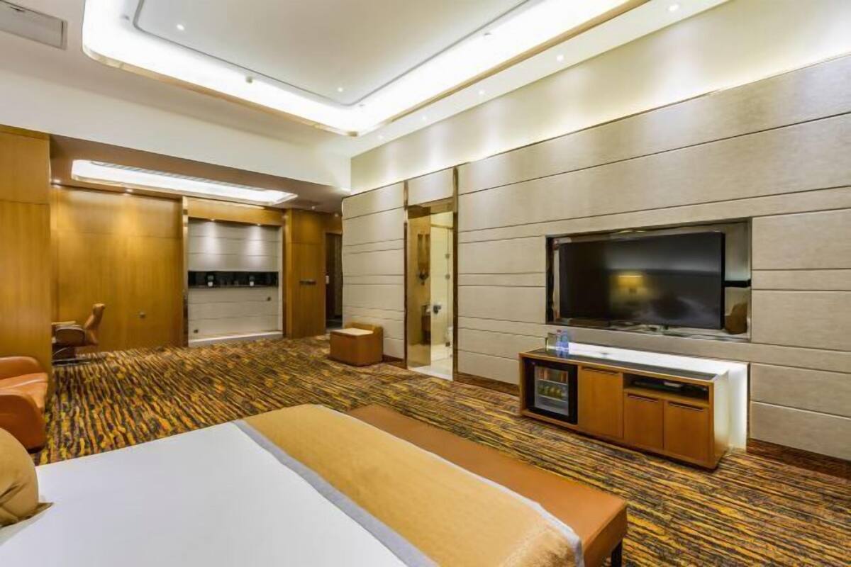 Habitación de hotel con una cama grande, televisor de pantalla plana, minibar y zona de estar.