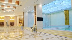 A spacious lobby with a large pool, a reception desk, and a modern ceiling design. - Jiujiang Hotel (Qian'an)