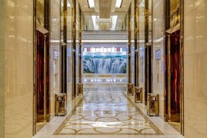 A corridor with a waterfall mural, polished marble floors, and gold accents. - Jiujiang Hotel (Qian'an)