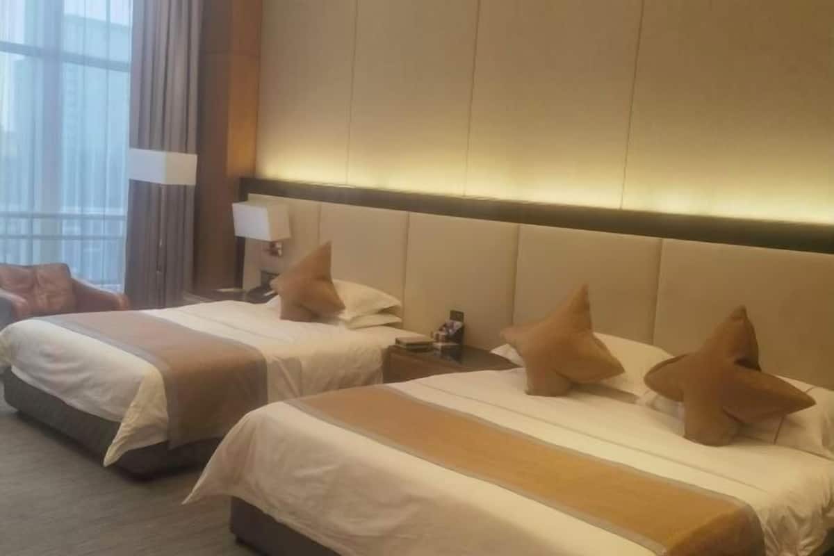 Habitación de hotel con dos camas, una mesita de noche, una lámpara y una ventana con cortinas.