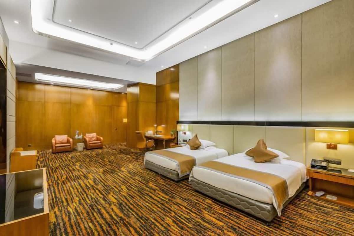 Una habitación de hotel con dos camas, un escritorio, una silla y una mesita.
