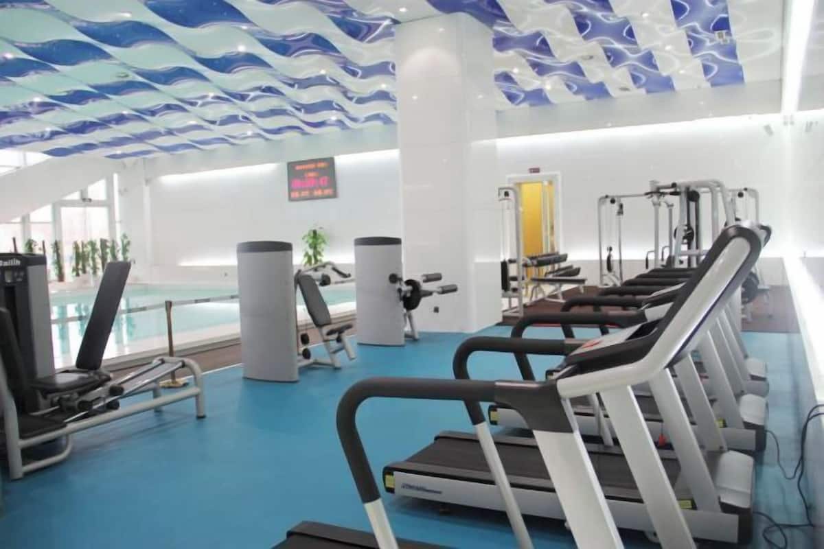 Un gimnasio con cintas de correr, máquinas de pesas y una zona de piscina.