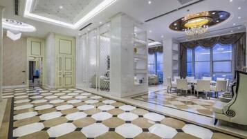 Un hall d’hôtel avec un sol à carreaux, un lustre et un espace repas comprenant des tables et des chaises.