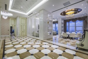 Un vestíbulo de hotel con piso a cuadros, un candelabro y un comedor con mesas y sillas.