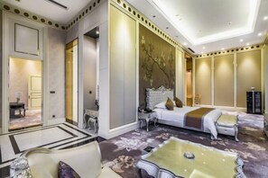 Hotellihuone, jossa on suuri sänky, oleskelualue pöydällä sekä koristeellinen seinä.