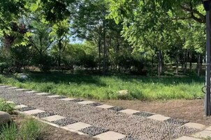 Un sendero de jardín con piedras que conducen a una zona de estar rodeada de árboles.