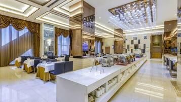 A spacious hotel lobby with a central reception desk, seating area, and a long counter with various amenities.