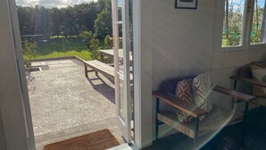 Et værelse med udsigt over en sø, en træbænk og en sofa med mønstrede puder.