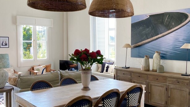 En spiseplads med et træbord, fire stole og en vase med blomster.