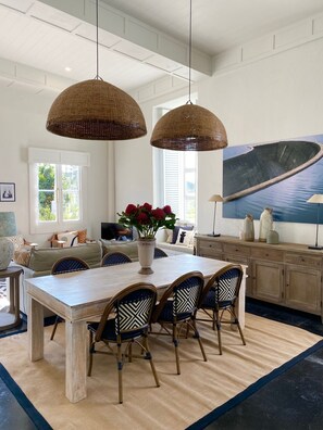 A dining area with a wooden table, four chairs, and a vase of flowers.