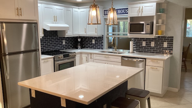 Una cocina moderna con una isla central, electrodomésticos de acero inoxidable y un salpicadero blanco y negro.
