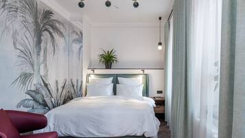 Un dormitorio con una cama grande, un cabecero con luces, una planta y una silla roja.