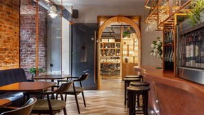 A bar area with wooden furniture, a brick wall, and a wooden archway leading to a bar. - Zalkind Hotel Rooms&Kitchen (Minsk)