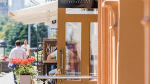 Un restaurante con terraza, un cartel que dice "WINE & PINSA" y un paisaje urbano al fondo.
