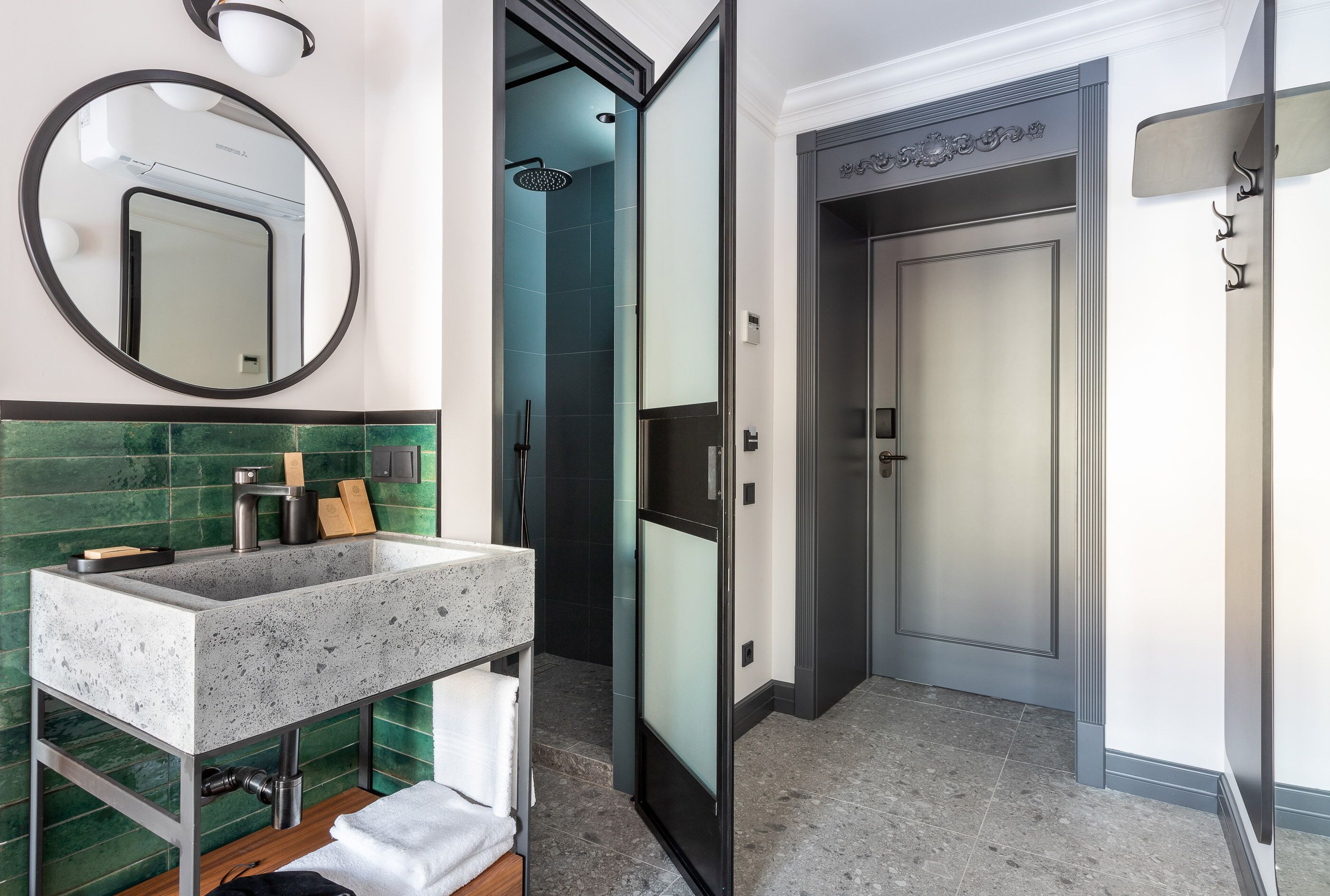 A modern bathroom with a granite sink, a mirror, a shower, and a door with a decorative panel.