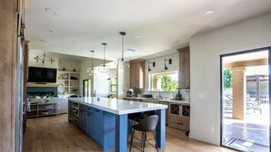 A modern kitchen with a large island, wooden cabinets, and pendant lighting. - Desert Pickle-ball Paradise in Scottsdale (Scottsdale)