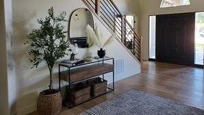 A staircase with wooden railings and a mirrored wall. There is a potted plant, a console table with books and decorative items, and a rug on the floor. - Desert Pickle-ball Paradise in Scottsdale (Scottsdale)