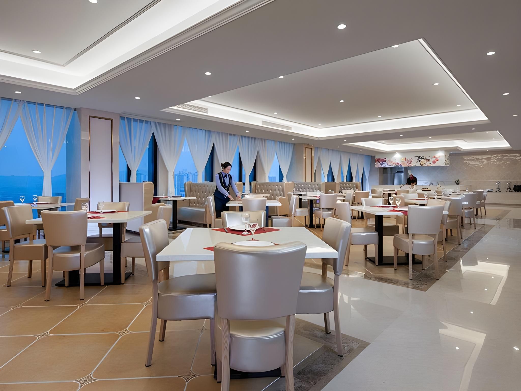 Un restaurante moderno con techo alto, iluminación empotrada y vista al mar.