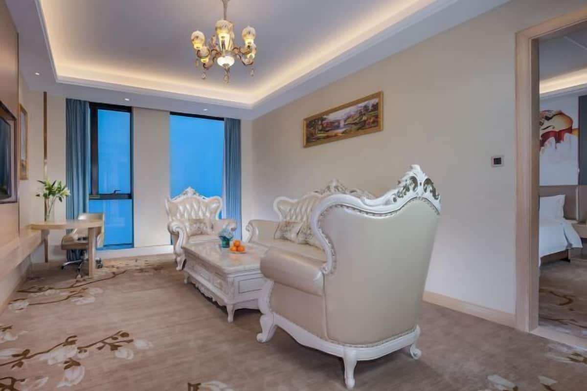 A spacious living room with a large window, a chandelier, and a sofa set.