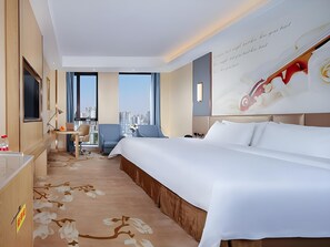 A hotel room with a large bed, a desk, a chair, a view of the city, and a wall with a decorative design.