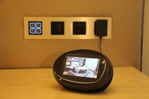 A digital device on a wooden surface with a wall-mounted control panel behind it. - Vienna International Hotel (Chongqing)