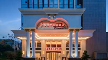 A hotel entrance with a prominent sign, large columns, and a modern building in the background.