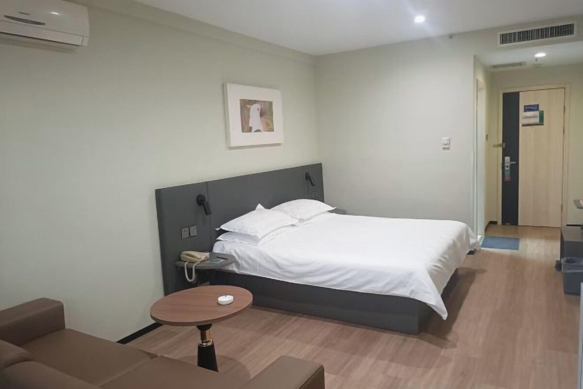 A hotel room with a bed, bedside table, and a small round table.