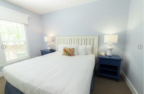 Relax in a spacious room with a large bed, two bedside tables, and a window with blinds.