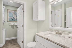 A bathroom with a white toilet, a sink with a marble countertop, and a cabinet above the mirror. - Windancer 307. Gulf Front Condo, Free Beach Service, Heated Pool, Grill. (Miramar Beach)