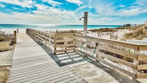 A wooden boardwalk leading to a beach with a sandy shore and a clear blue sky. - Windancer 307. Gulf Front Condo, Free Beach Service, Heated Pool, Grill. (Miramar Beach)