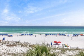 A beach with white sand, blue umbrellas, and a clear sky. - Windancer 307. Gulf Front Condo, Free Beach Service, Heated Pool, Grill. (Miramar Beach)