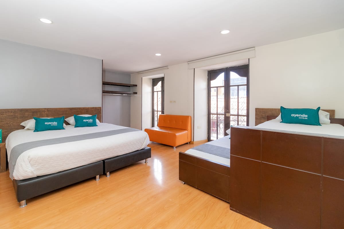 A hotel room with two beds, a sofa, and a large window.