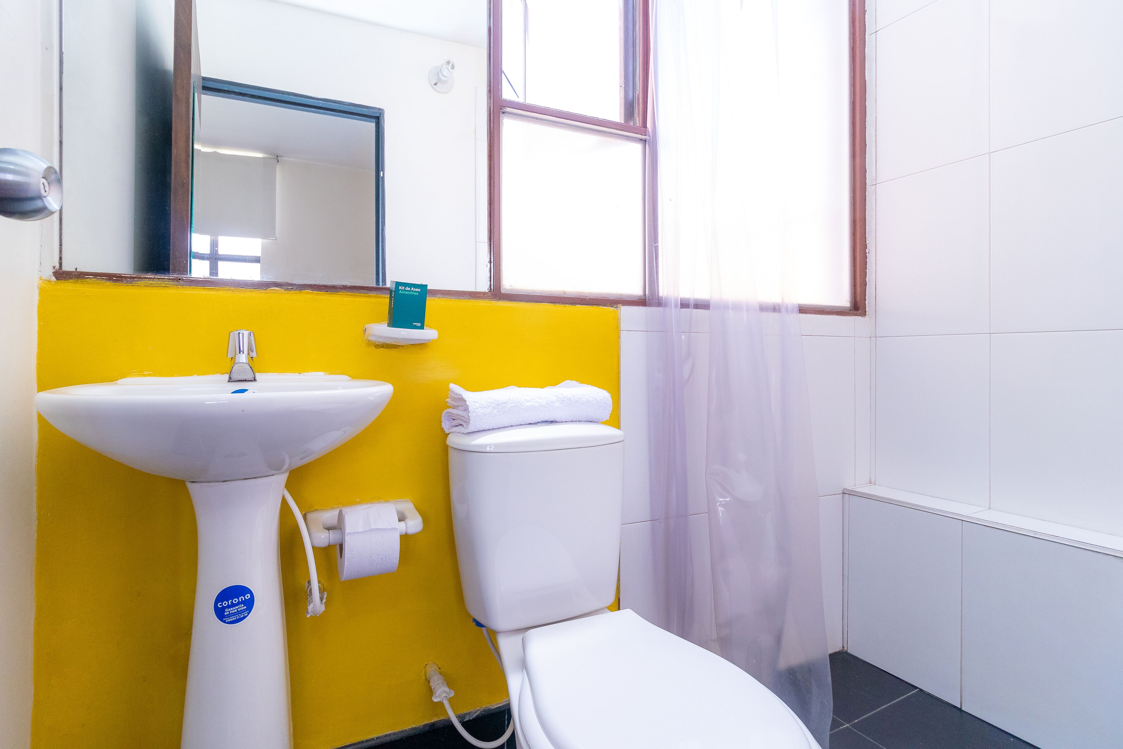 Un baño con pared amarilla, lavabo blanco y retrete.
