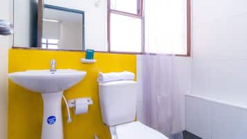Un baño con pared amarilla, lavabo blanco y retrete.